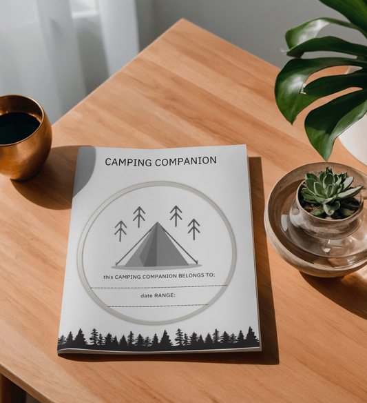 A wood table with the camping companion on top, with plants and a cup beside it
