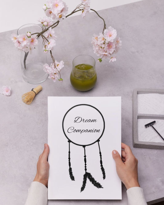 hands holding the dream companion journal, with a drink, a flower, and a Zen garden